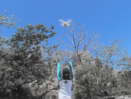 A C3 staff member raises hands and observes a drone overhead. Community Centre Conservation - C3 Philippines: Dugong Conservation